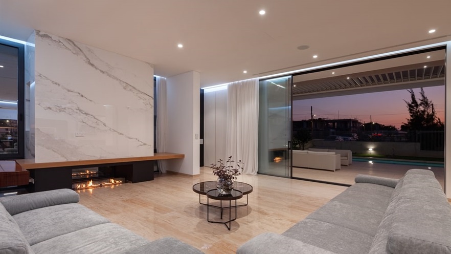 Living room with large sofas and fireplace, open aluminum windows with view to the terrace