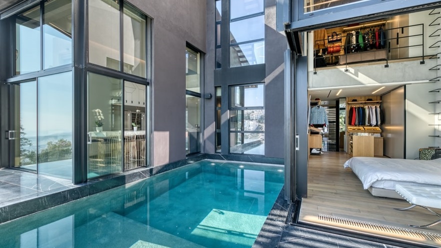 The pool is next to the bedroom that can be seen through the open window